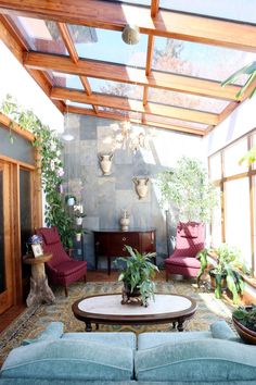 a living room filled with lots of furniture and plants on top of the tables in front of them