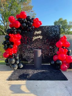 a black and red balloon arch with happy birthday balloons