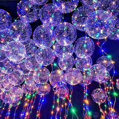 many balloons are floating in the air with lights all around them and on top of each other