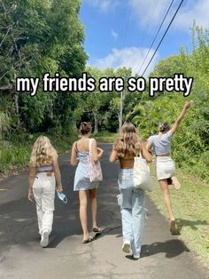 three girls walking down the road with their arms in the air and one girl holding her hand up