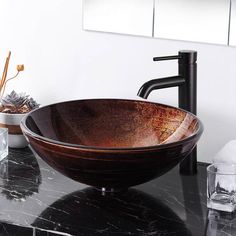 a bowl shaped sink sitting on top of a black counter next to a faucet