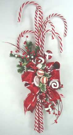 two candy canes are attached to the wall with red ribbons and bows on it