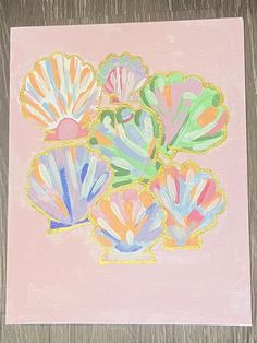 an image of colorful seashells in pastel colors on pink paper with wood background