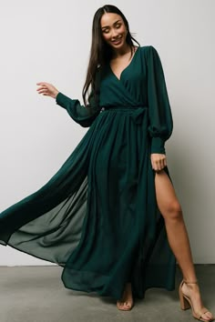 a woman in a long green dress posing for the camera with her legs spread out