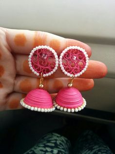 pink and white earrings are being held in someone's hand