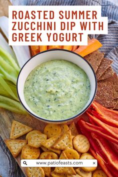 a bowl of dip surrounded by crackers, celery and carrots