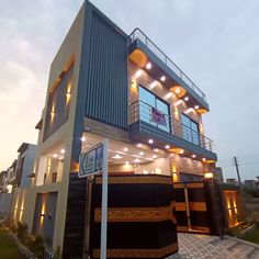 a two story house that has lights on the windows and balconies above it