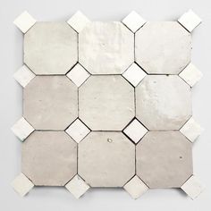 a white and grey tiled wall with hexagonal tiles on the bottom, in different sizes