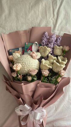 a bunch of stuffed animals wrapped in pink paper and tied to a white ribbon on a bed