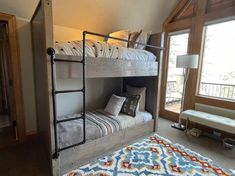 a bunk bed sitting in the corner of a room next to a window and rug