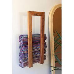 a stack of towels hanging on the wall next to a mirror and wooden rack with folded towels