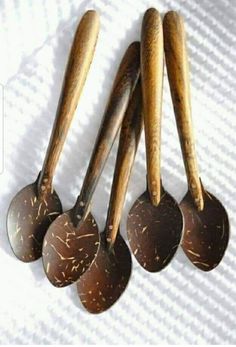 four wooden spoons are lined up next to each other on a white cloth surface