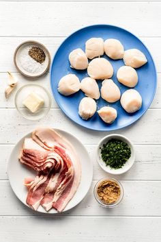 the ingredients to make an appetizer laid out on a white wooden table including meat, cheese and seasonings