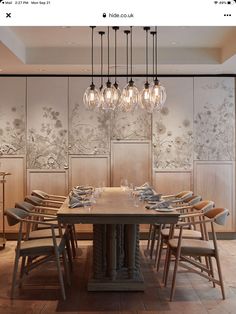 a dining room table with chairs and lights hanging from the ceiling