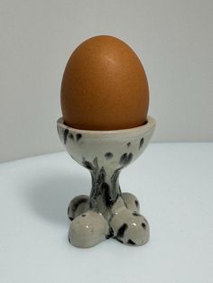 an egg sitting in a ceramic bowl on top of a white tablecloth with black speckles