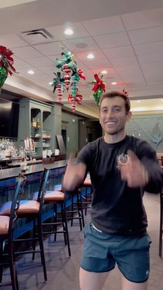 a man standing in front of a bar with chairs and decorations hanging from the ceiling