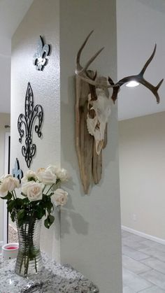 two deer heads mounted on the wall next to vases with white roses in them