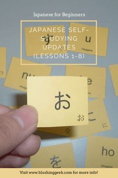 a hand holding up a piece of yellow paper with japanese writing on it and the words,