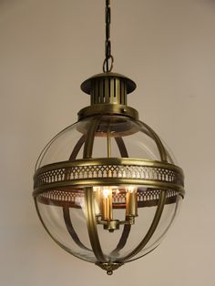 a light fixture hanging from the ceiling with two candles in it's glass globe