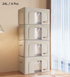 three white suitcases stacked on top of each other in front of a window with curtains