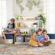 two children are sitting on the floor reading books in front of a map and window