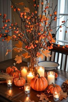 a table topped with candles and pumpkins on top of a wooden table covered in leaves