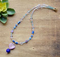 a blue and pink beaded necklace next to a flower