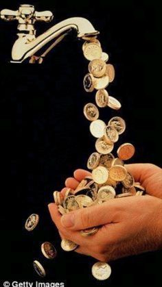 a person's hand is pouring coins into a faucet