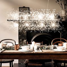 a dining room table with candles, plates and cups on it in front of a fireplace