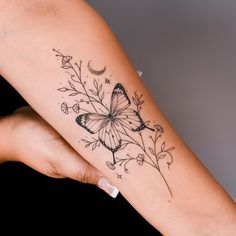 a woman's arm with a butterfly and flowers tattoo on the left side of her arm