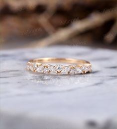 a gold wedding band with five diamonds on it sitting on top of a marble slab