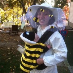 a young child dressed as a bee holding a baby