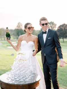 a bride and groom holding champagne glasses in front of a wine cooler on the golf course