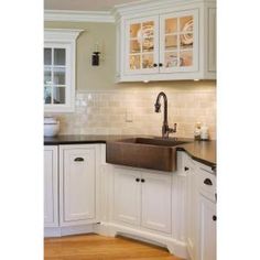 a kitchen with white cabinets and black counter tops, an old fashioned sink is in the center