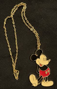 a mickey mouse necklace with a red shirt on it's chest and a gold chain