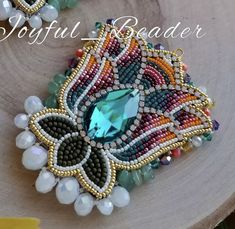 a close up of a brooch on a wooden surface with beads and pearls around it