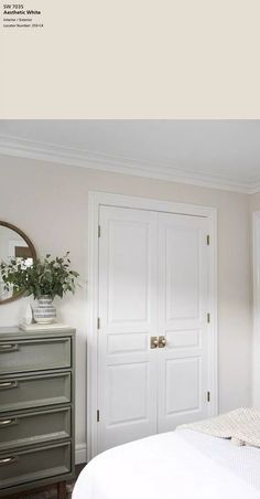 a white bedroom with two doors and a mirror on the wall next to a bed