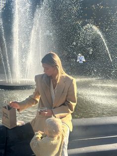 a woman and child standing in front of a fountain