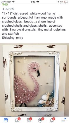 a pink flamingo in a white frame with sea shells and starfish on it