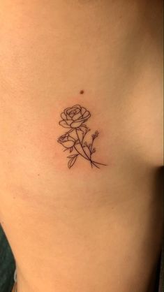 a woman's stomach with a small flower tattoo on her side ribcage