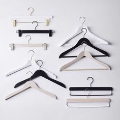 four hangers with black, white and beige clothes hanging from them on a white background