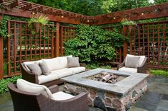 an outdoor living area with couches, fire pit and pergolated trellis