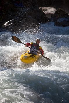 a man in a yellow kayak is riding through some rapids on the river water