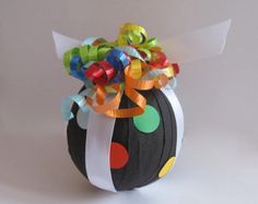 a black ball with colorful ribbons and bows on it's top is sitting on a white surface