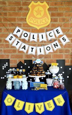 a police station themed birthday party with food and decorations on a table in front of a brick wall