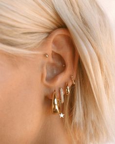 a close up of a person wearing gold earring with diamonds on the inside of their ears