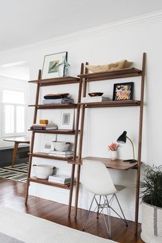 a wooden ladder leaning against a white wall in a room with a desk and chair