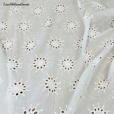 the fabric is white with brown spots on it and has an interesting pattern that looks like flowers