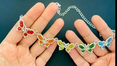 two hands holding an open chain with multicolored hearts on it and the other hand is