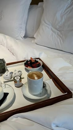 a tray with two cups of coffee and some pastries on it next to a bowl of strawberries